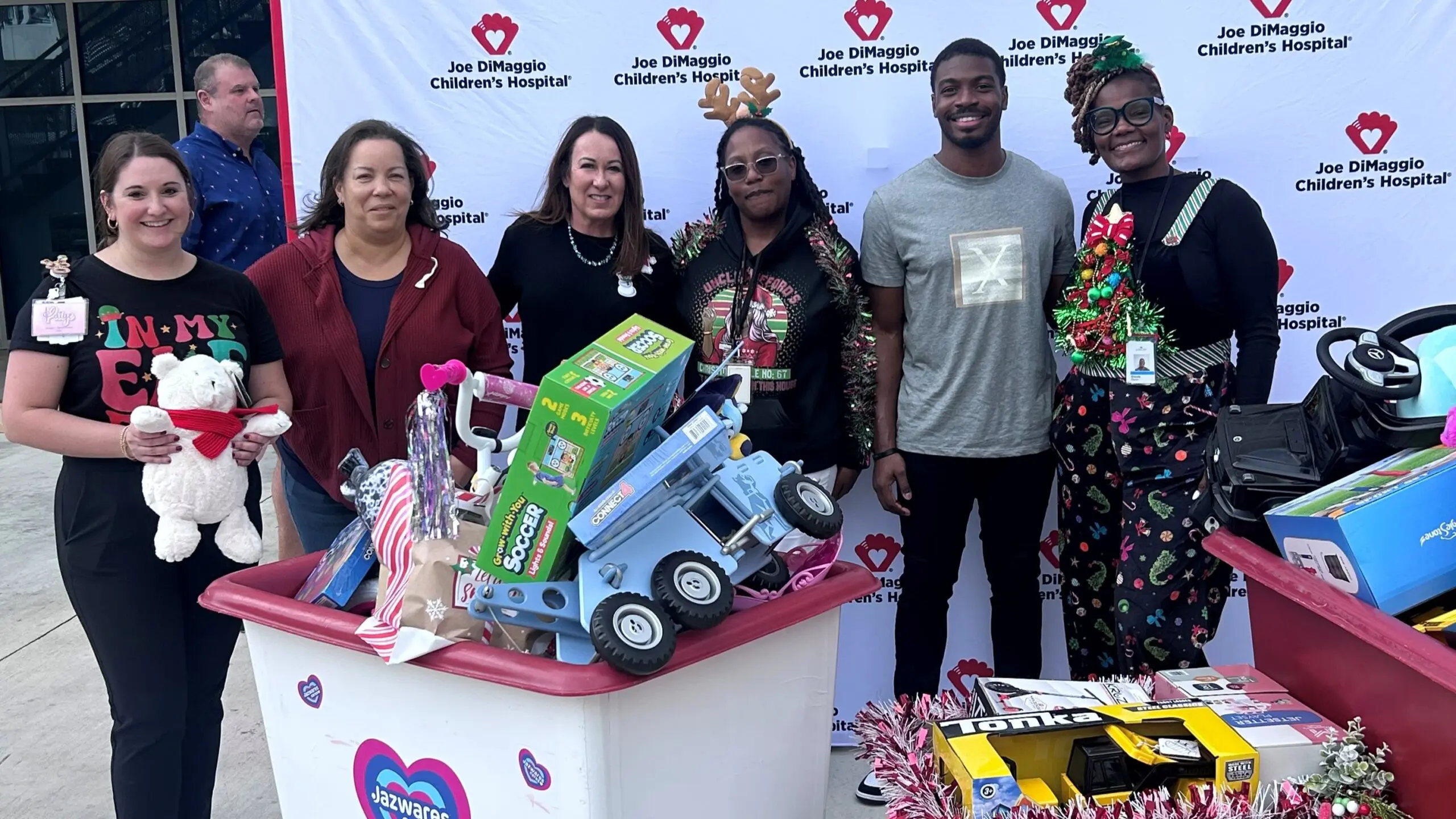 A group of Comcast Employees poses with loads of toys to give out at Joe DiMaggio Children's Hospital.