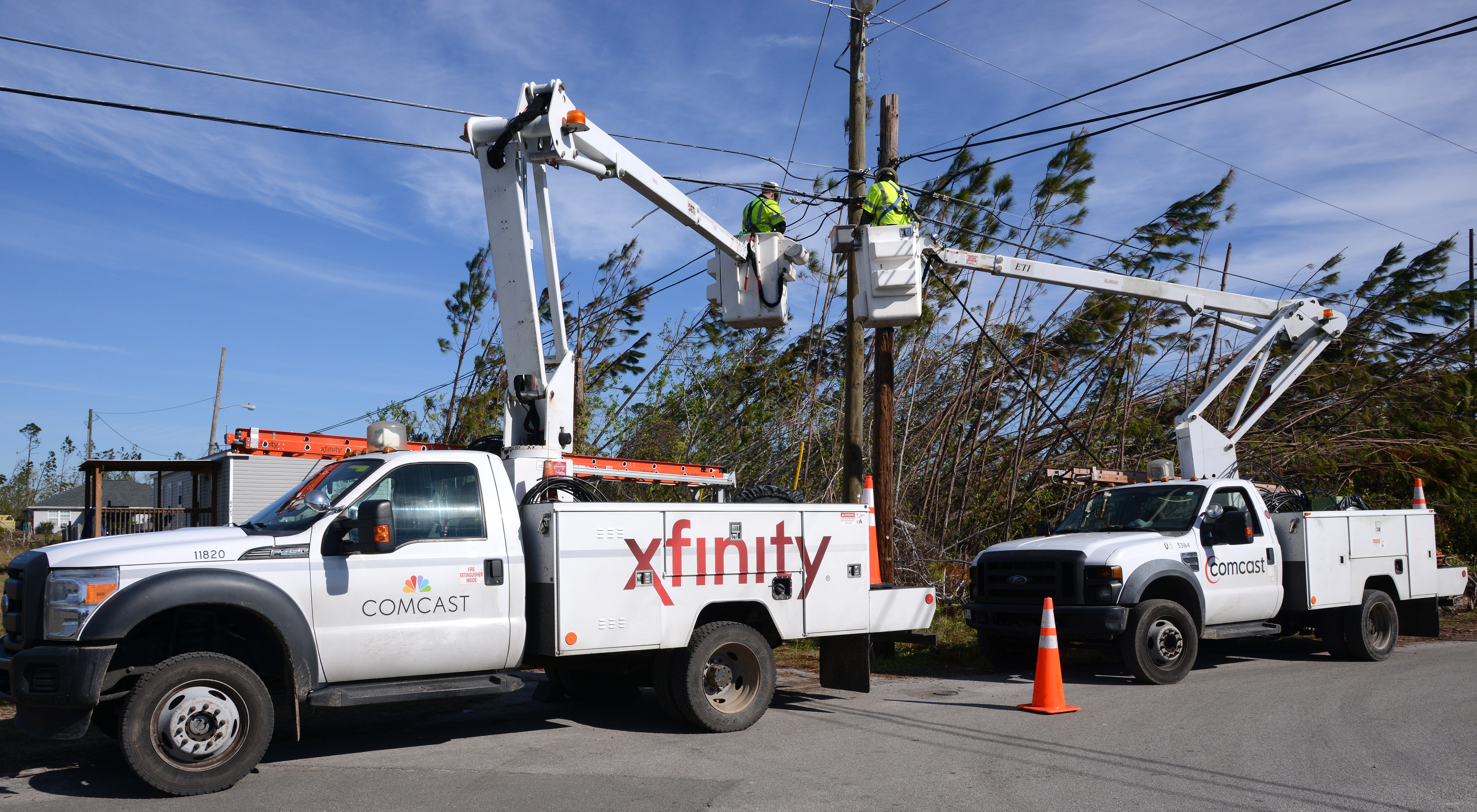 Xfinity linemen in cranes fixing a phone line.